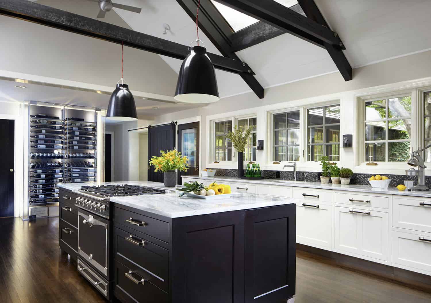 dramatic kitchen with a black island and white perimeter cabinets