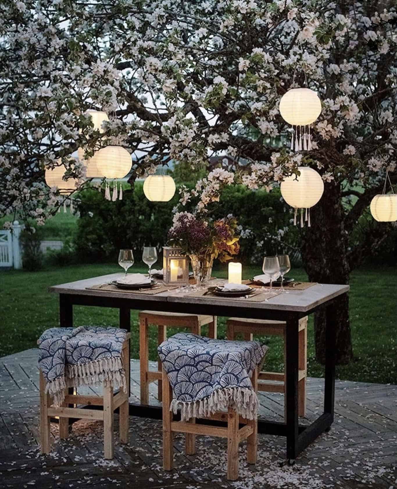 outdoor dining area underneath a blooming apple tree with solar cell lamps
