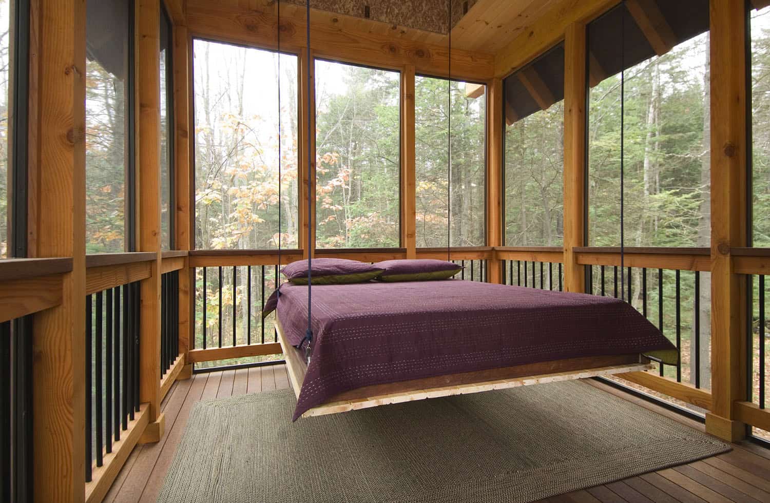 simple screened in sleeping porch with a hanging bed with burgundy comforter and pillows 