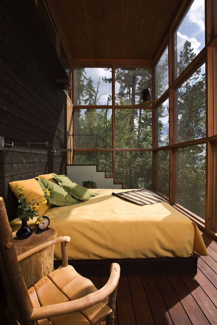windowed sleeping porch with bright sunlight on large yellow bed with yellow and green pillows 