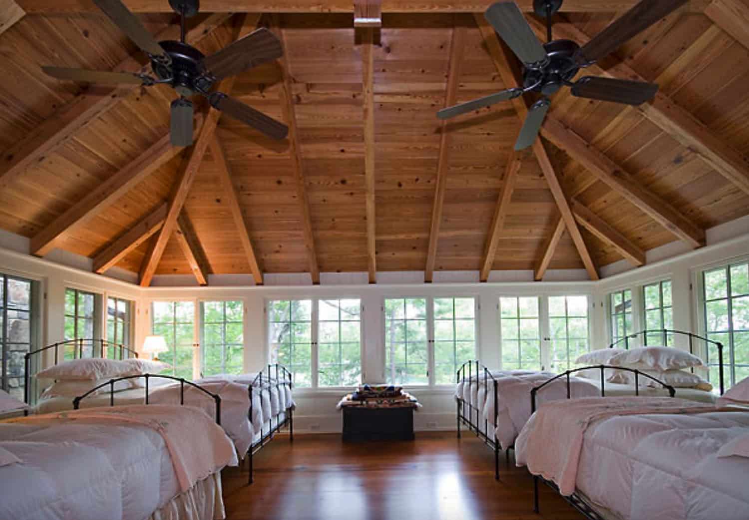 large sleeping porch with two fans on ceiling and four large beds with white blankets