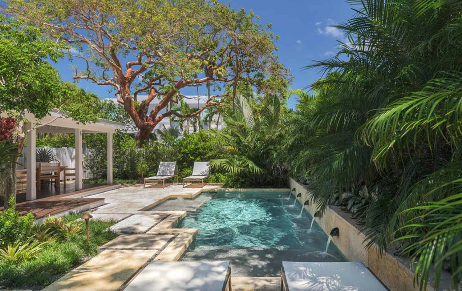 small rectangle pool with chairs, trees and a sitting area in the background 