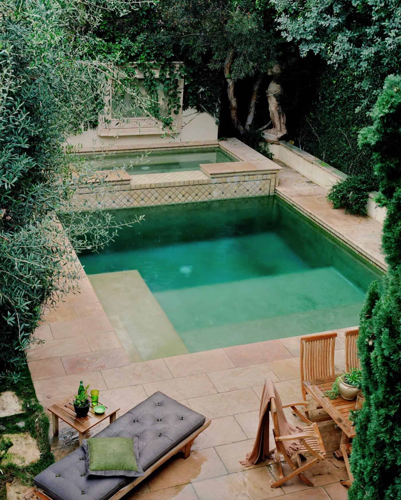 square pool with hot tub on the side with cement deck and sitting area