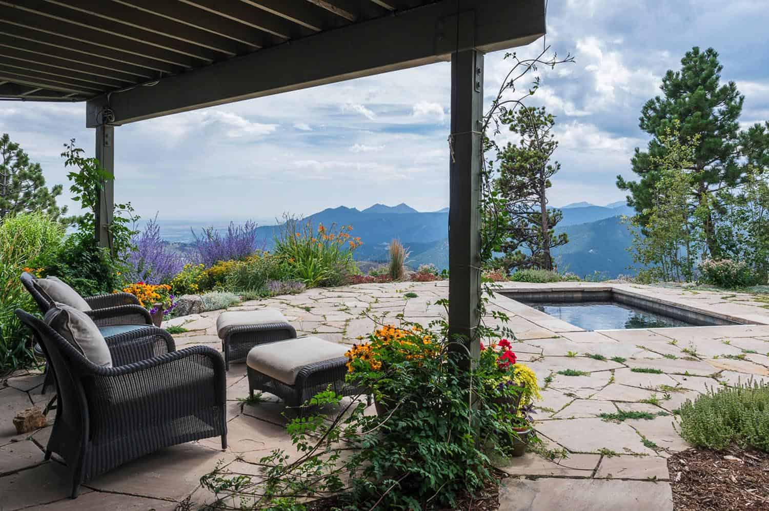 small rectangle pool with rock deck overlooking mountains and a sitting area under pergola 