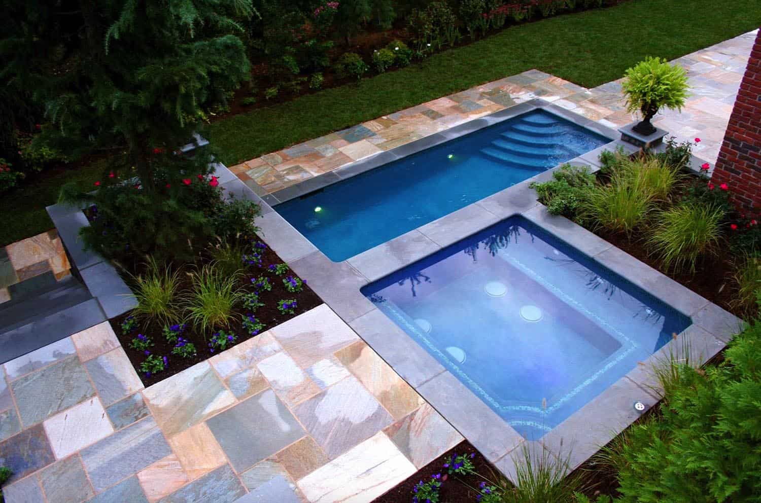 overhead view of pool and hot tub with colorful cement deck and green grassy area 