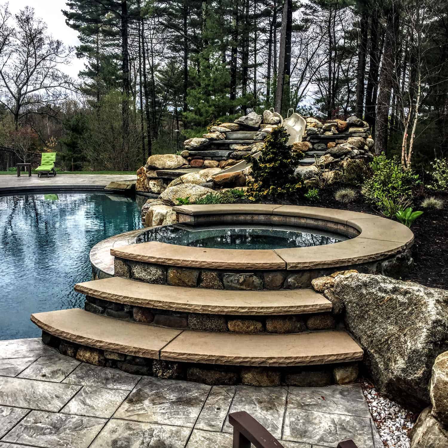 outdoor jacuzzi overlooking pool with slide on rocks