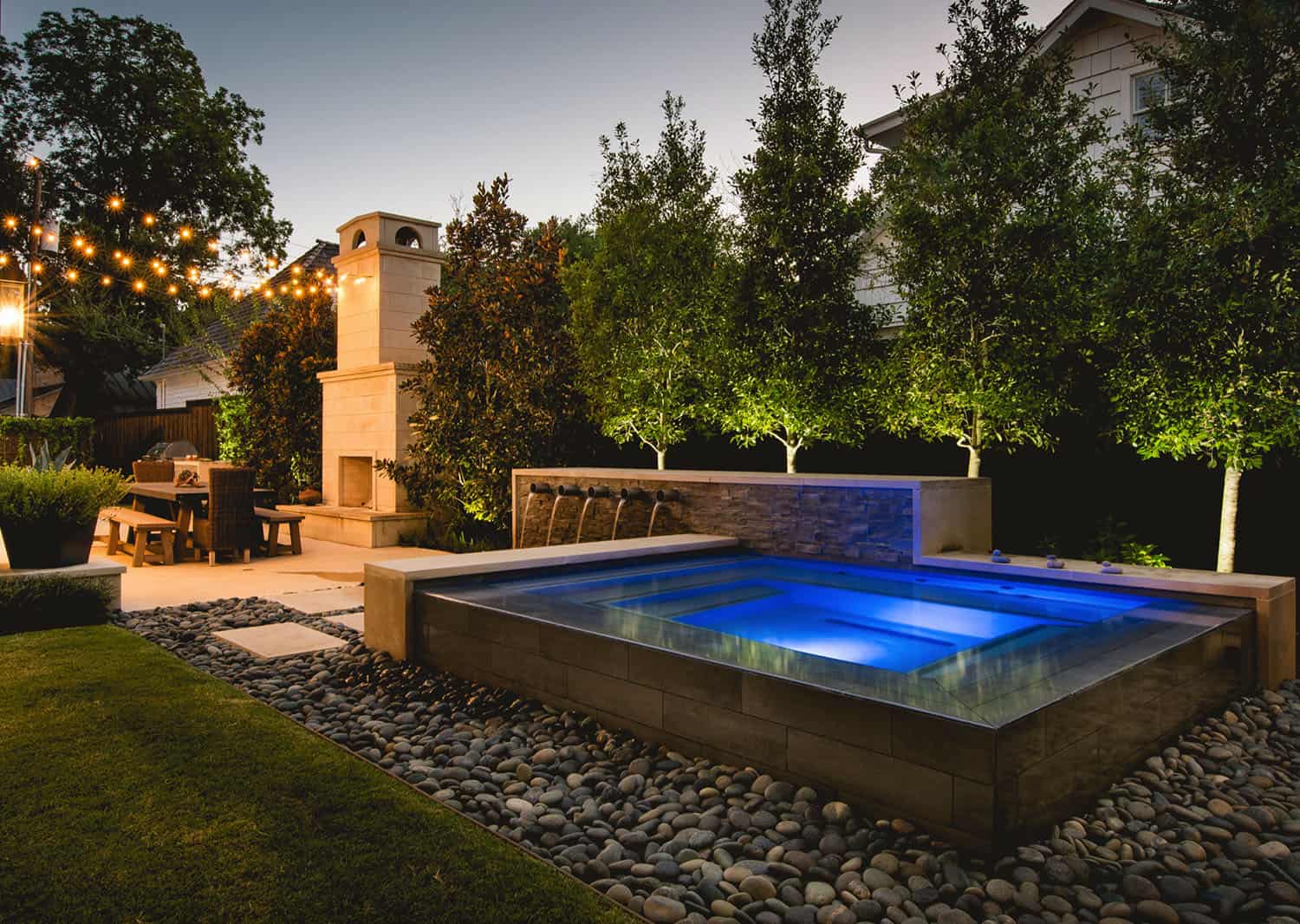 square hot tub with rock siding and sitting area and trees in the background 