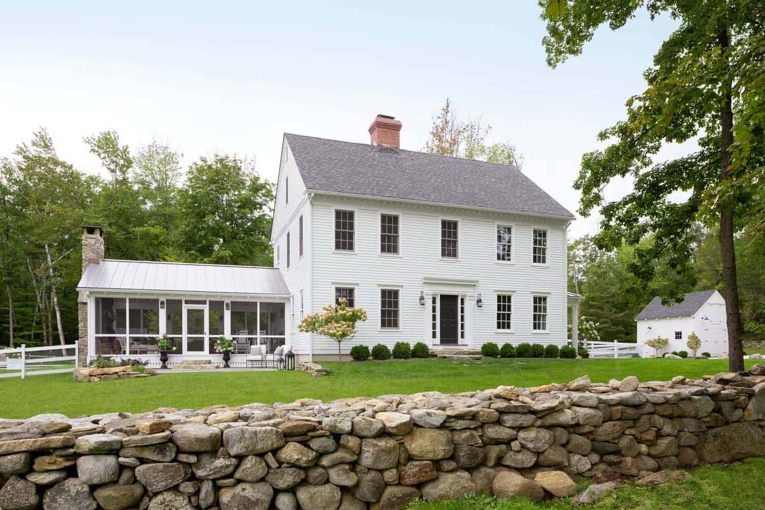 white country farmhouse exterior with a stone wall