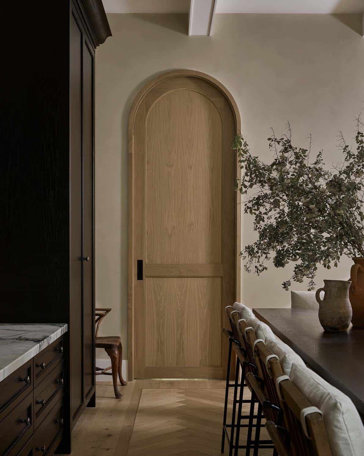 transitional style kitchen with an arched door leading into the pantry