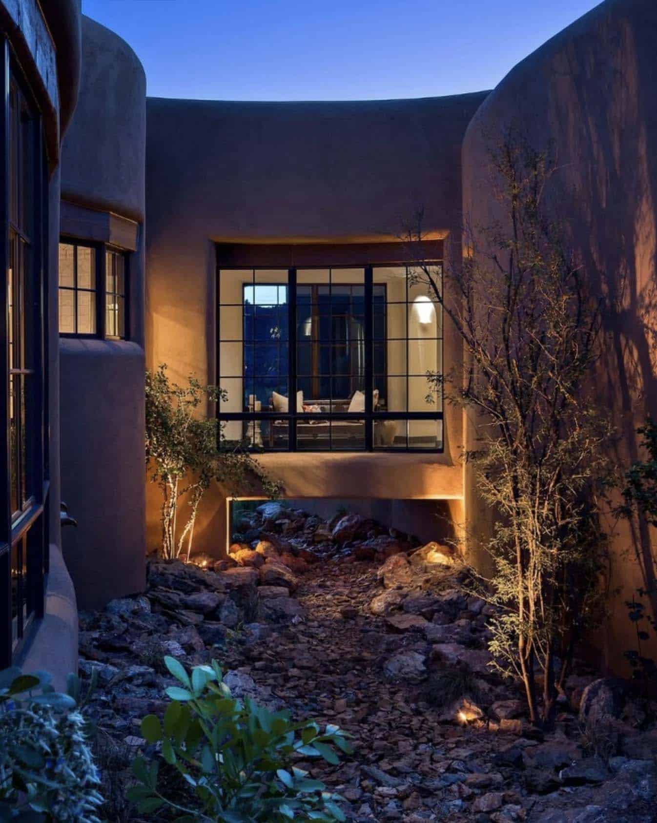 southwestern style home exterior with a bridge at night