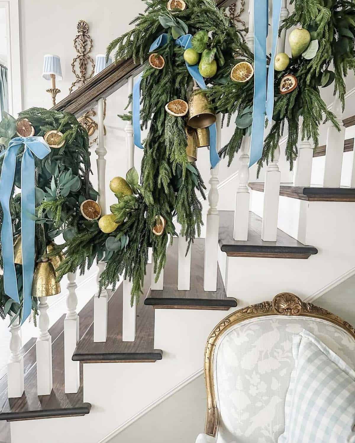 staircase railing with pine garland and blue velvet bows