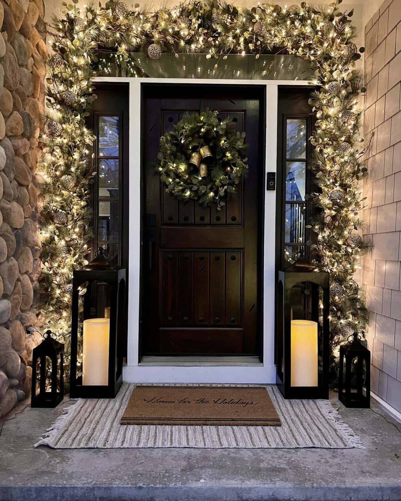 christmas decorated front porch with pre-lit garland, a wreath and lanterns