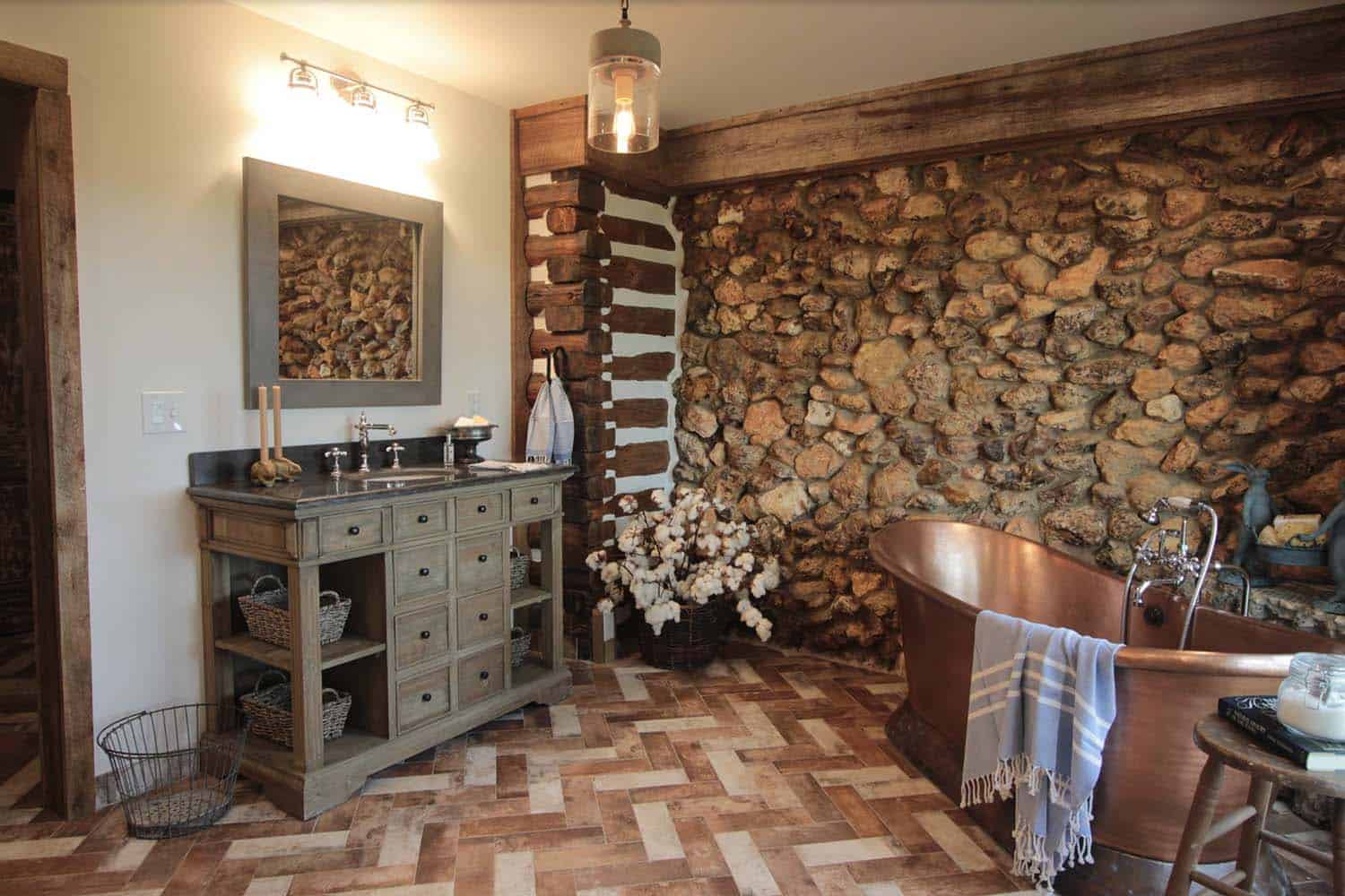 rustic bathroom with a wood vanity, copper tub and rock accent wall