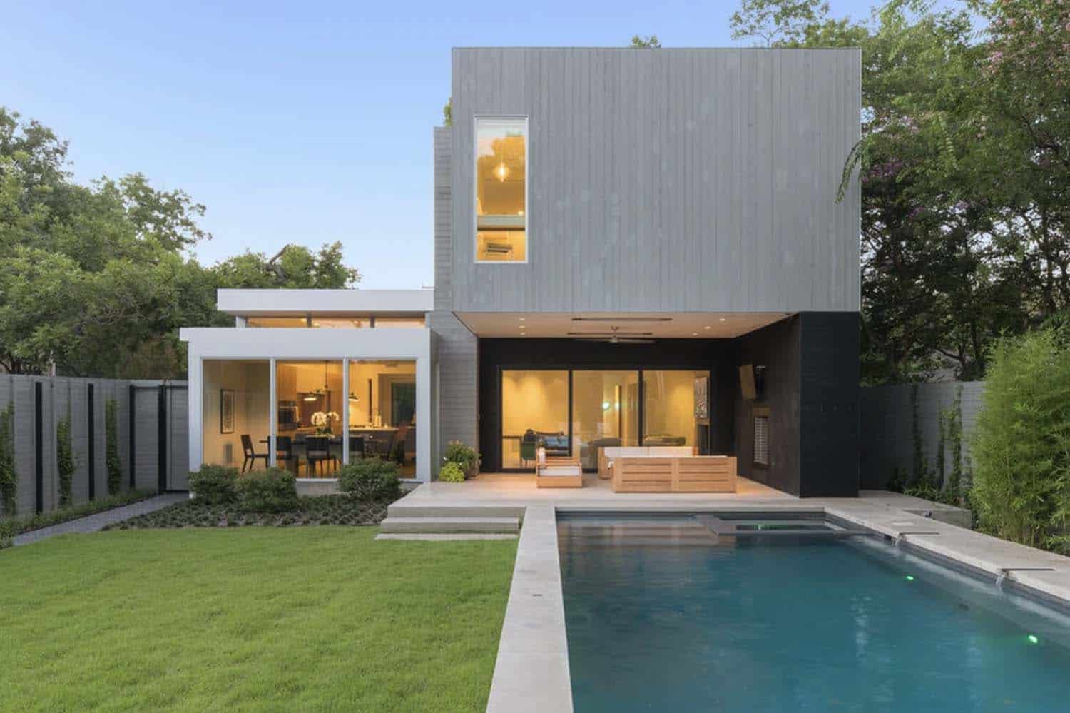 modern home backyard exterior at dusk with a pool view
