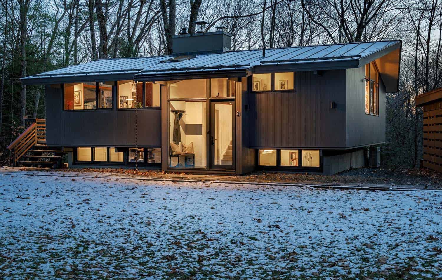 midcentury modern deck house exterior with snow at dusk