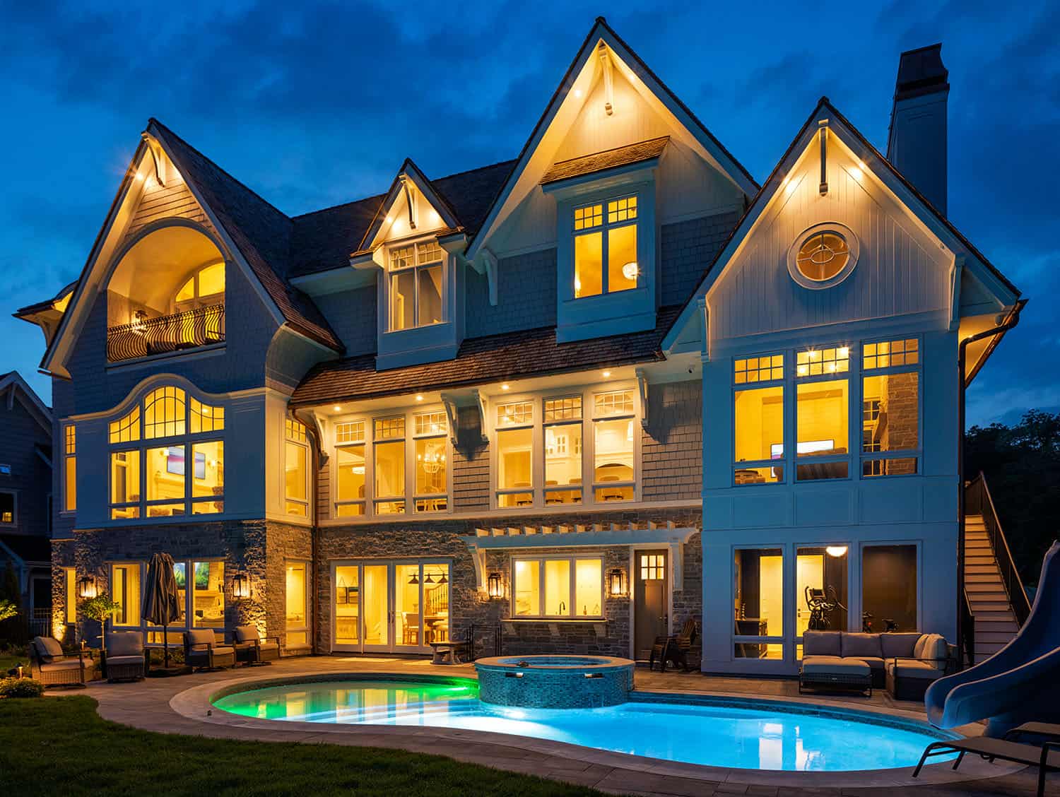 cape cod cottage style house exterior with a pool at dusk