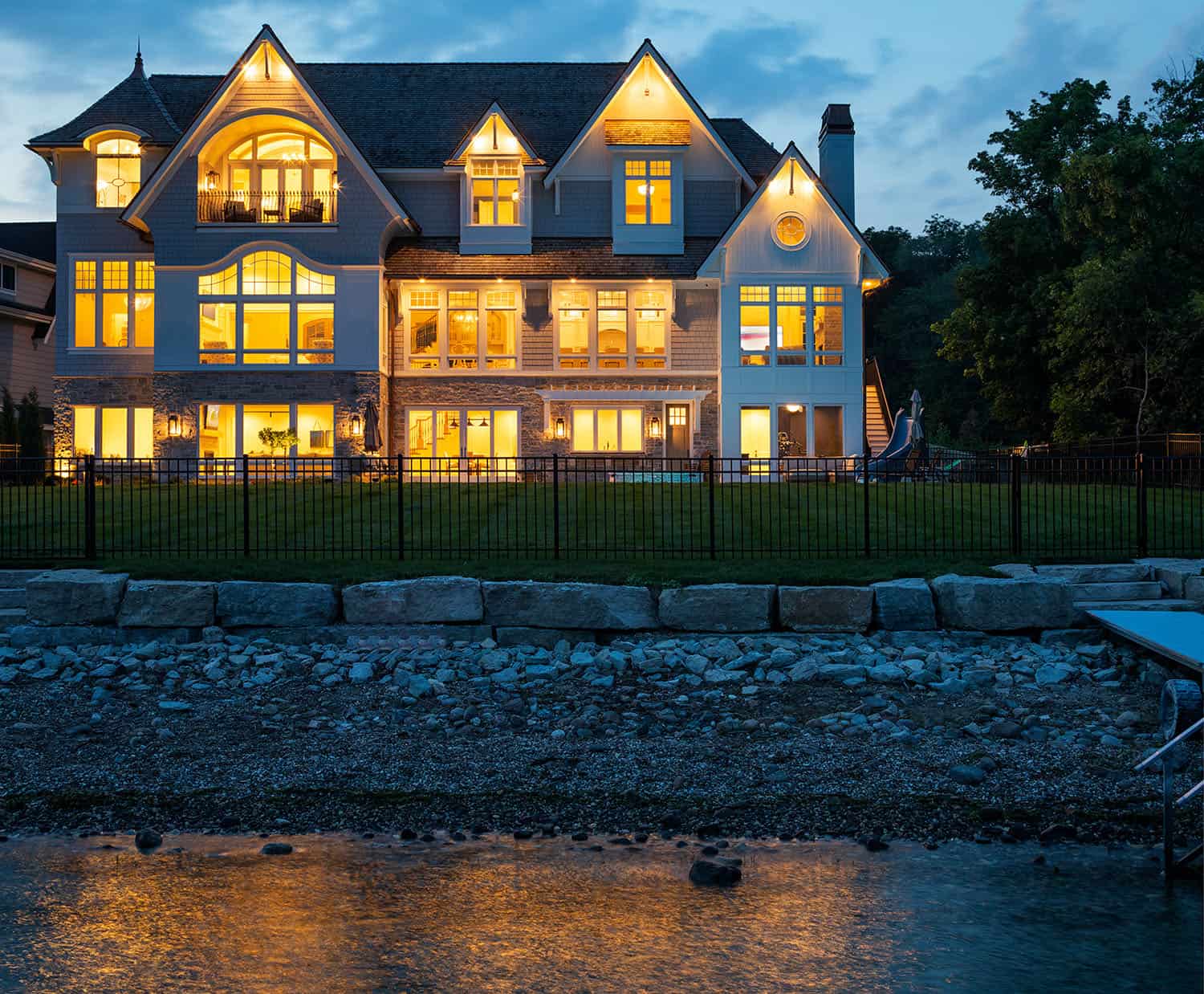 cape cod cottage style house exterior view from the lake at dusk