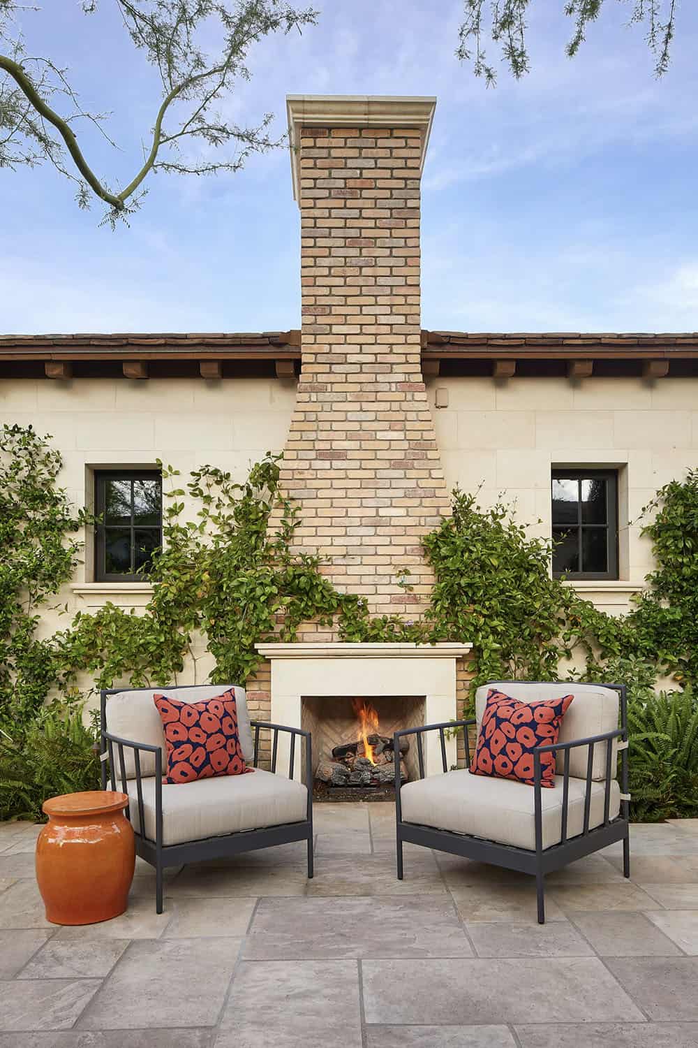 outdoor fireplace with two chairs and a garden stool