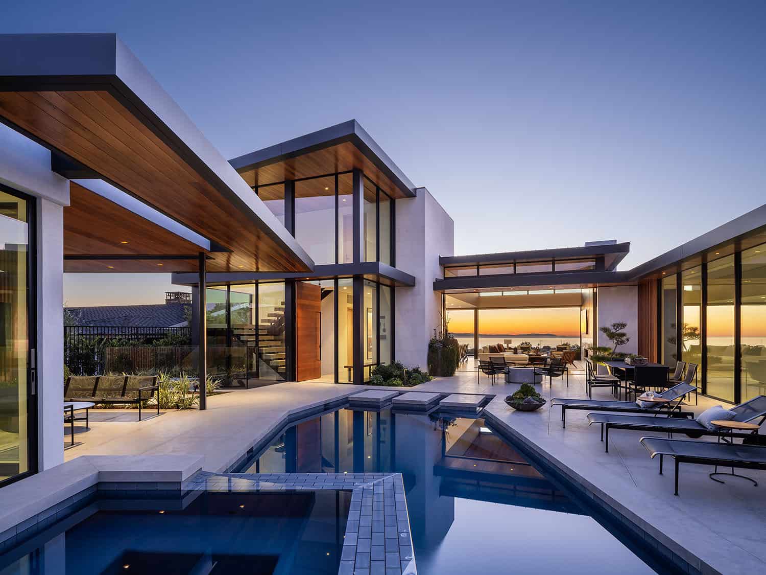 contemporary beach house exterior with a pool at dusk