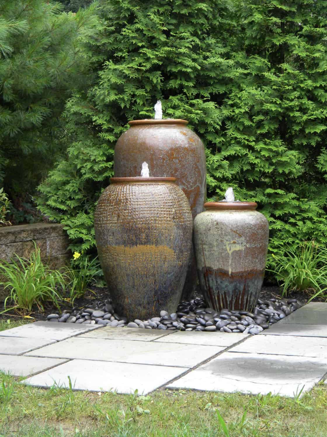 jar fountains on a patio with rocks underneath