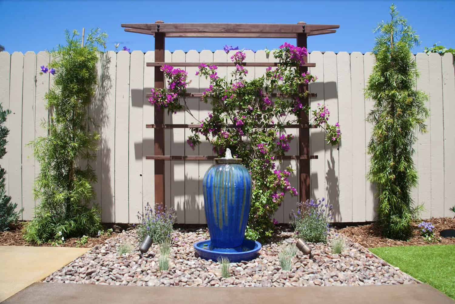 blue water fountain with a trellis and bougainvillea