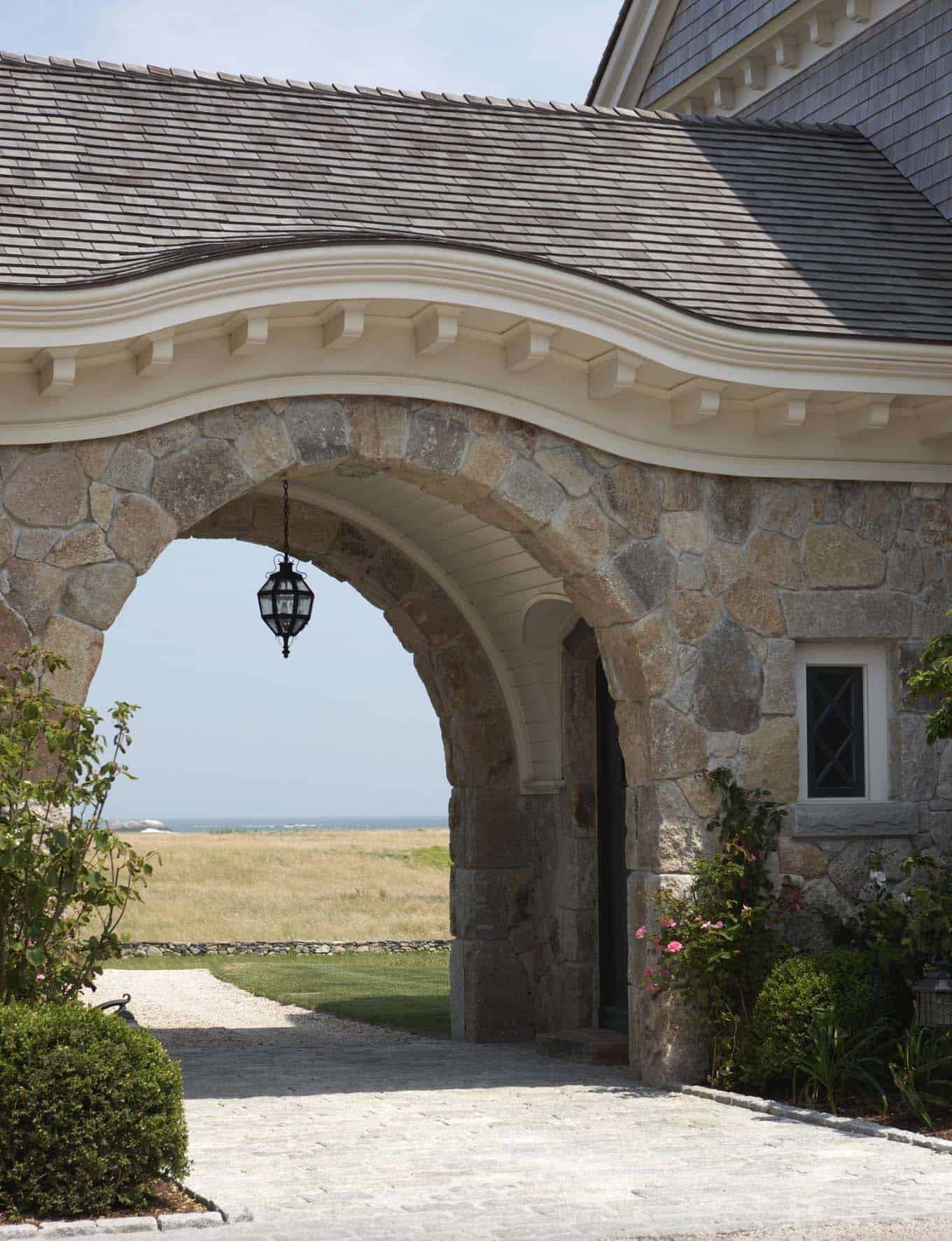 oceanfront home with a stone entry arch and views of the ocean