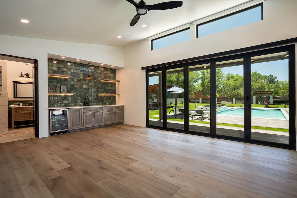 modern-rustic-home-bar-with-green-backsplash-tile-and-sliding-glass-doors-leading-out-to-the-back-patio