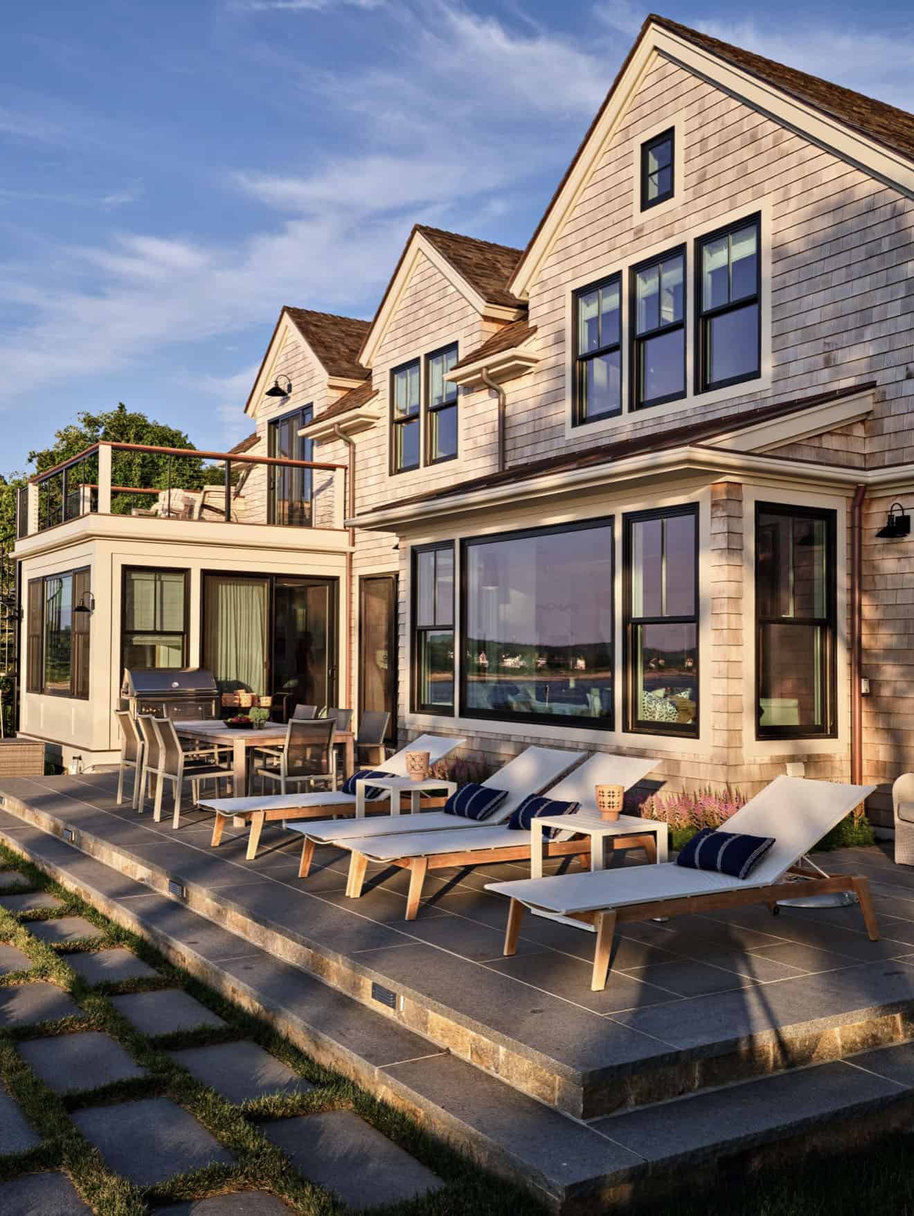 shingle-style-waterfront-house-exterior-with-a-patio-and-lounge-chairs