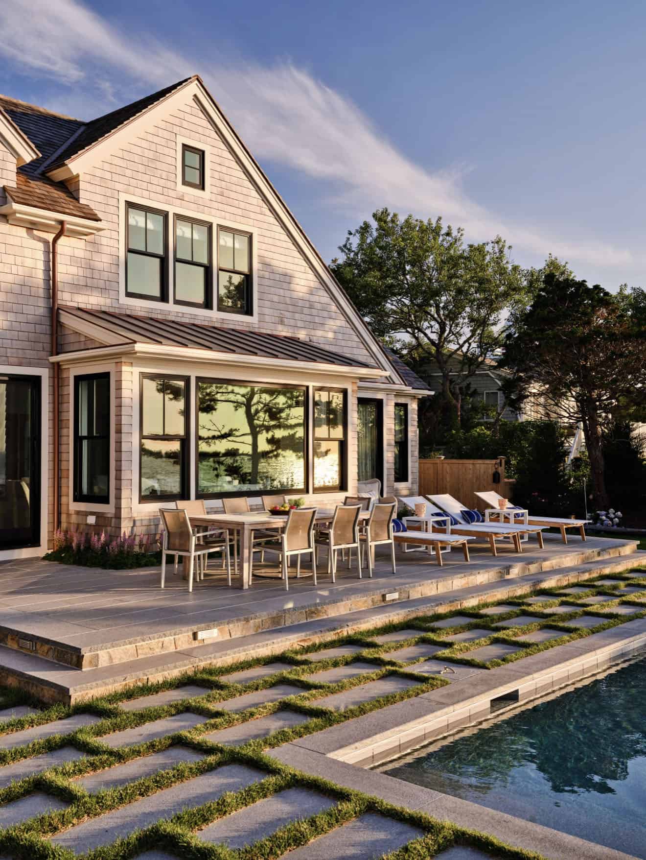 shingle-style-waterfront-house-exterior-with-a-patio-and-lounge-chairs