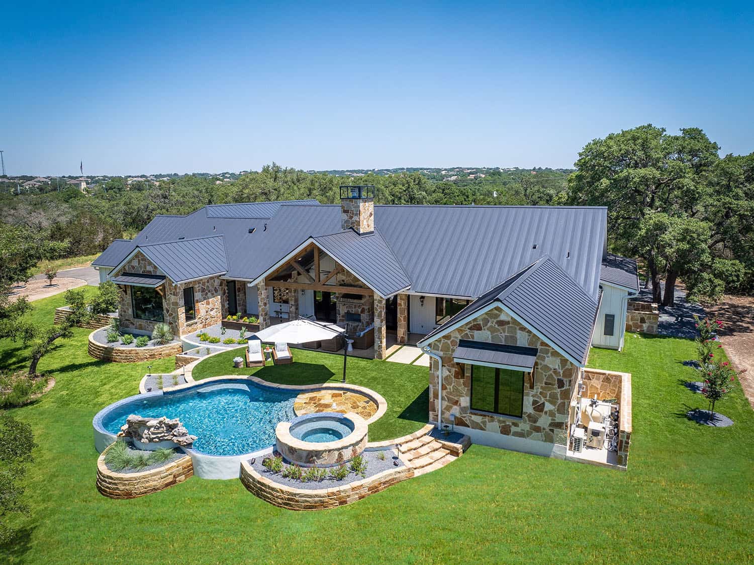 Texas-hill-country-style-home-exterior-with-a-pool-aerial-view