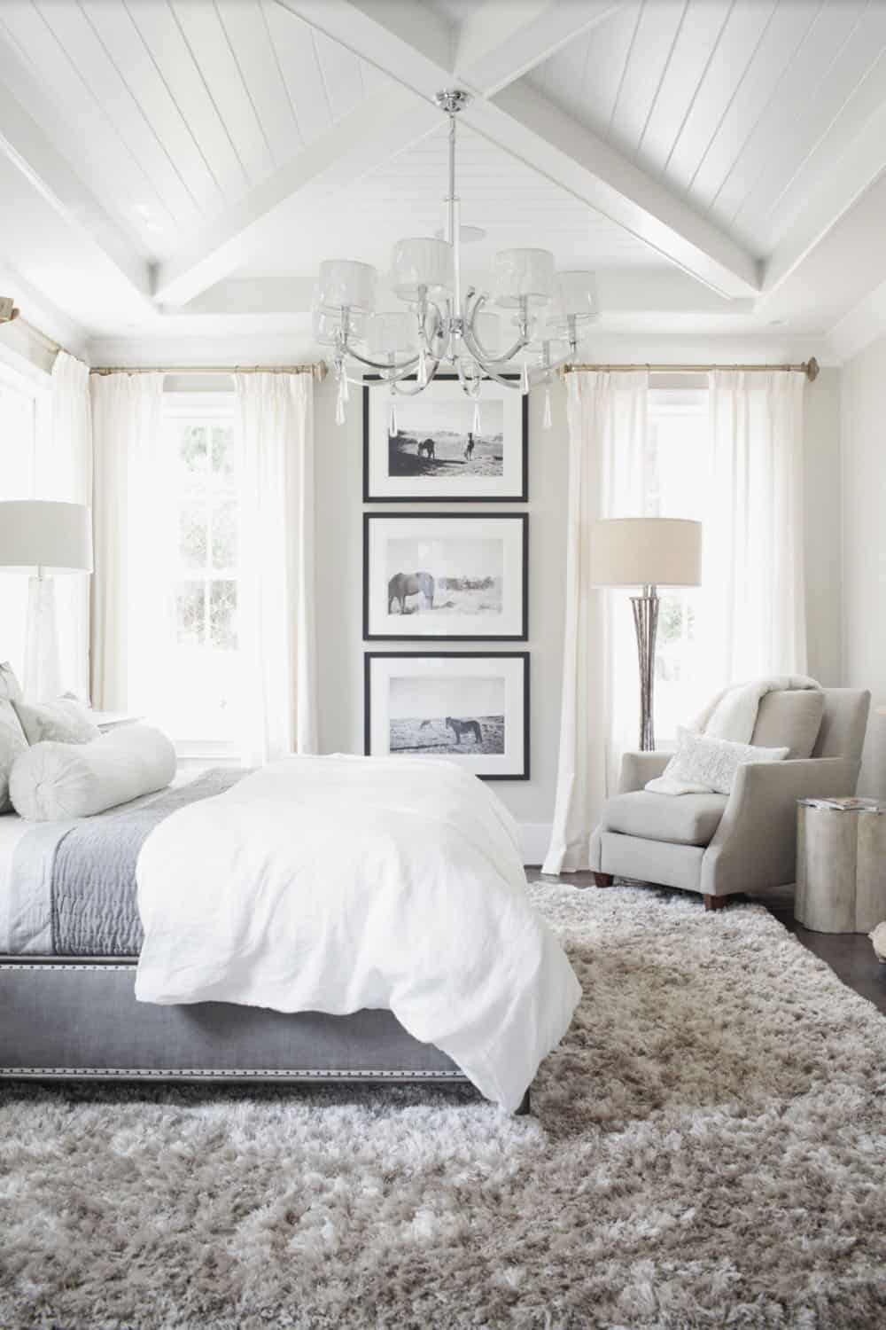 transitional style bedroom with a tray ceiling with x-beams and a large chandelier