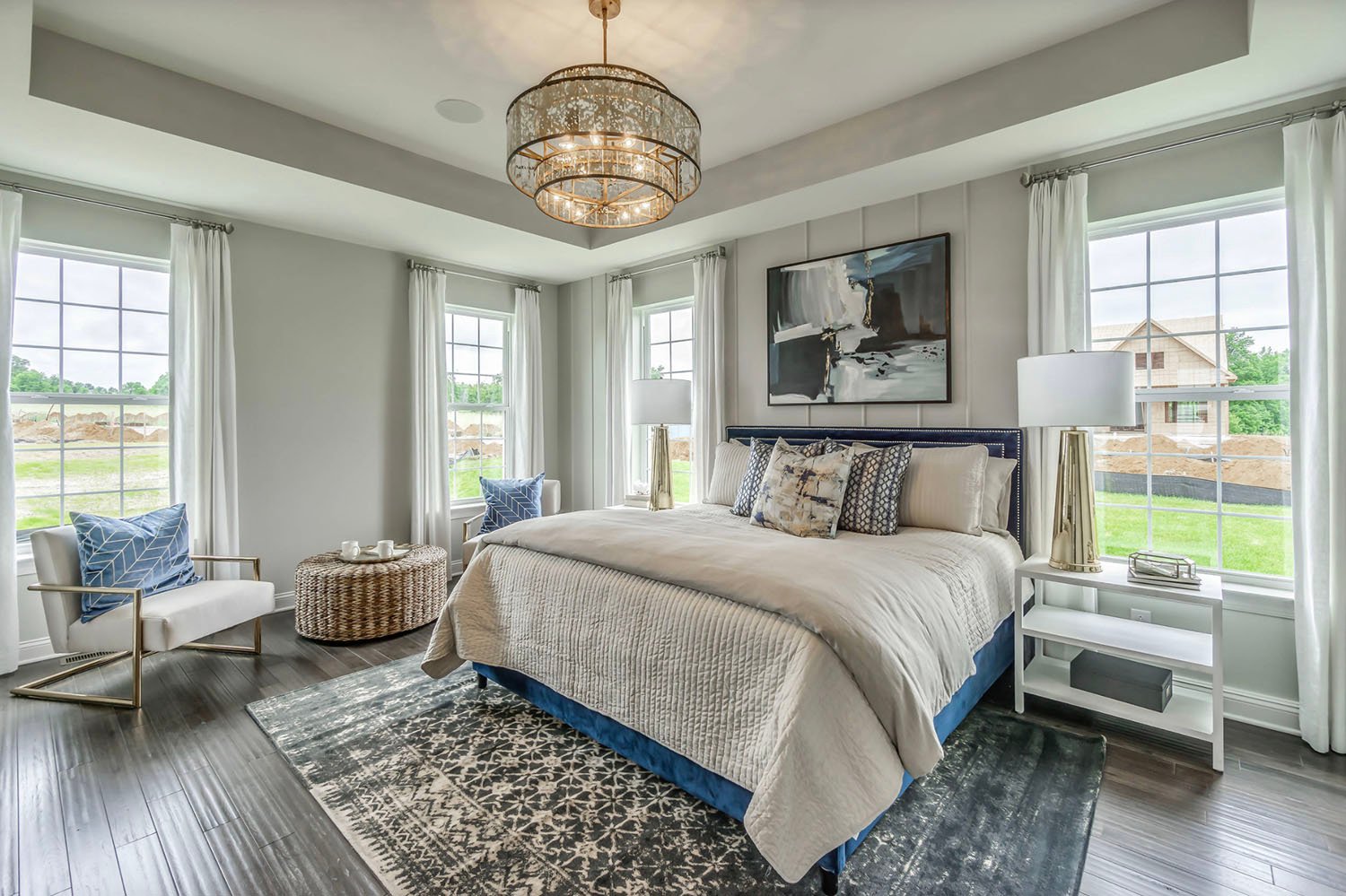 transitional style bedroom with a chandelier and artwork above the headboard