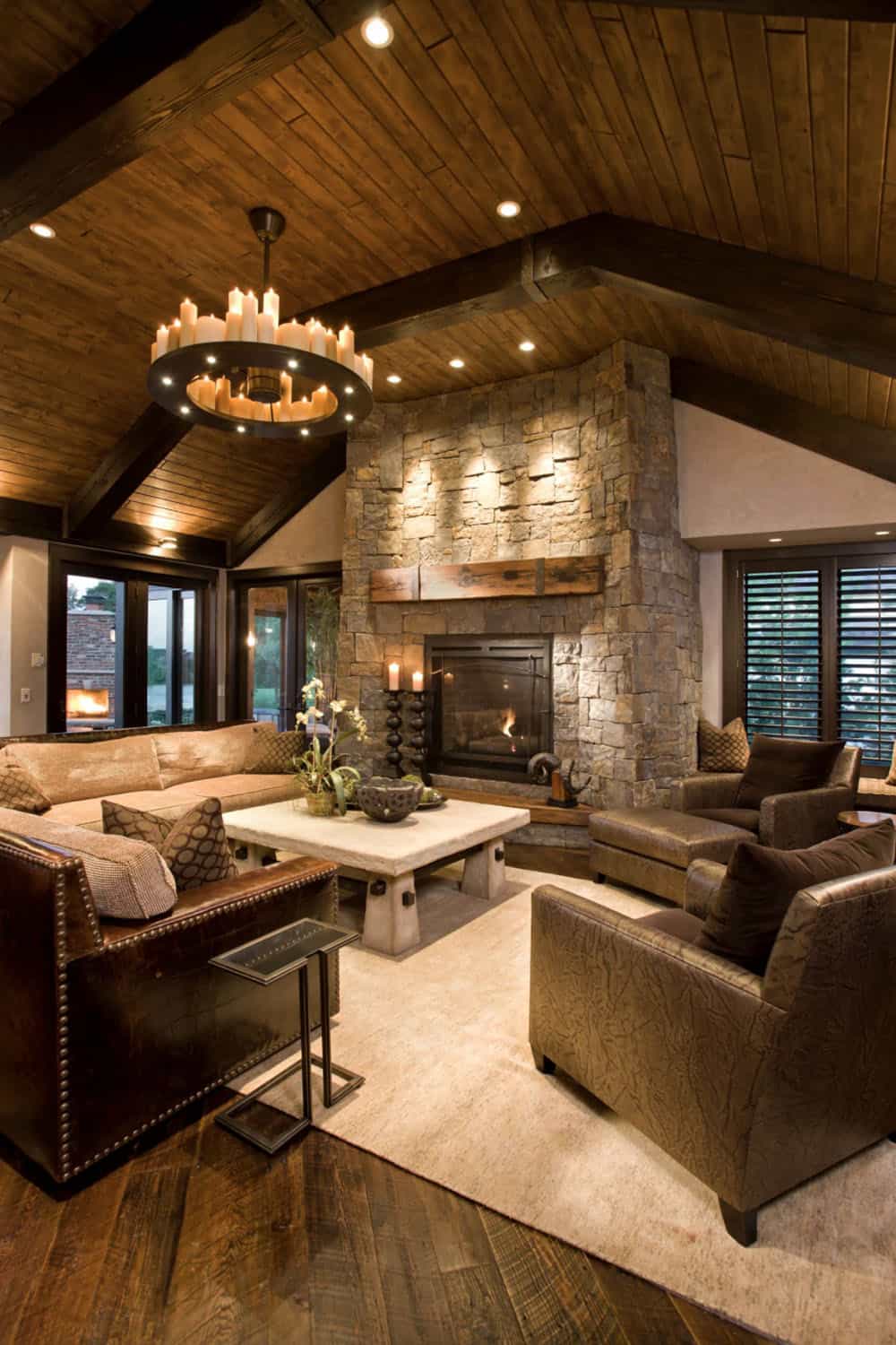 modern rustic living room with a stone fireplace and large chandelier