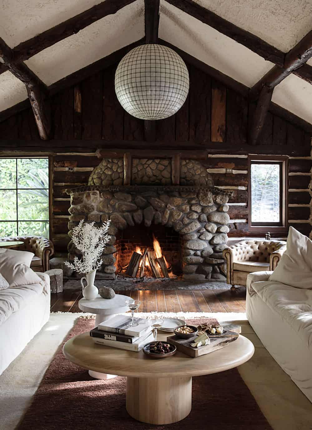 rustic modern living room with a massive stone fireplace and capiz shell chandelier