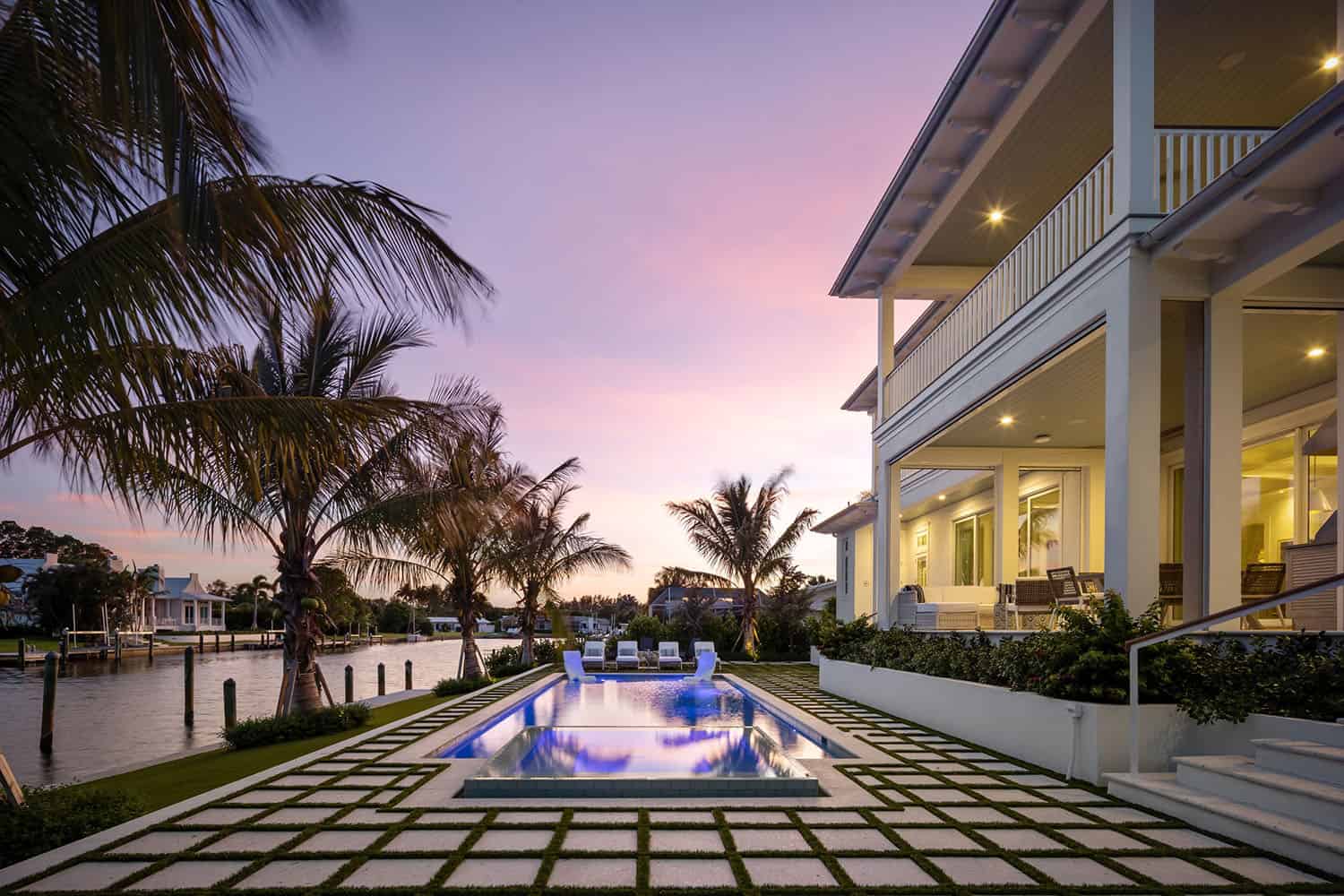 contemporary coastal home with a pool at dusk