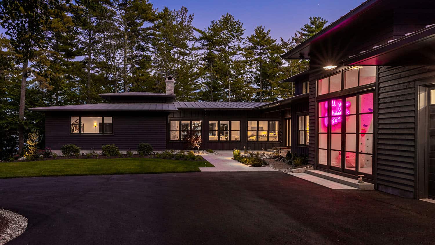 contemporary prairie style home exterior with a front driveway at dusk