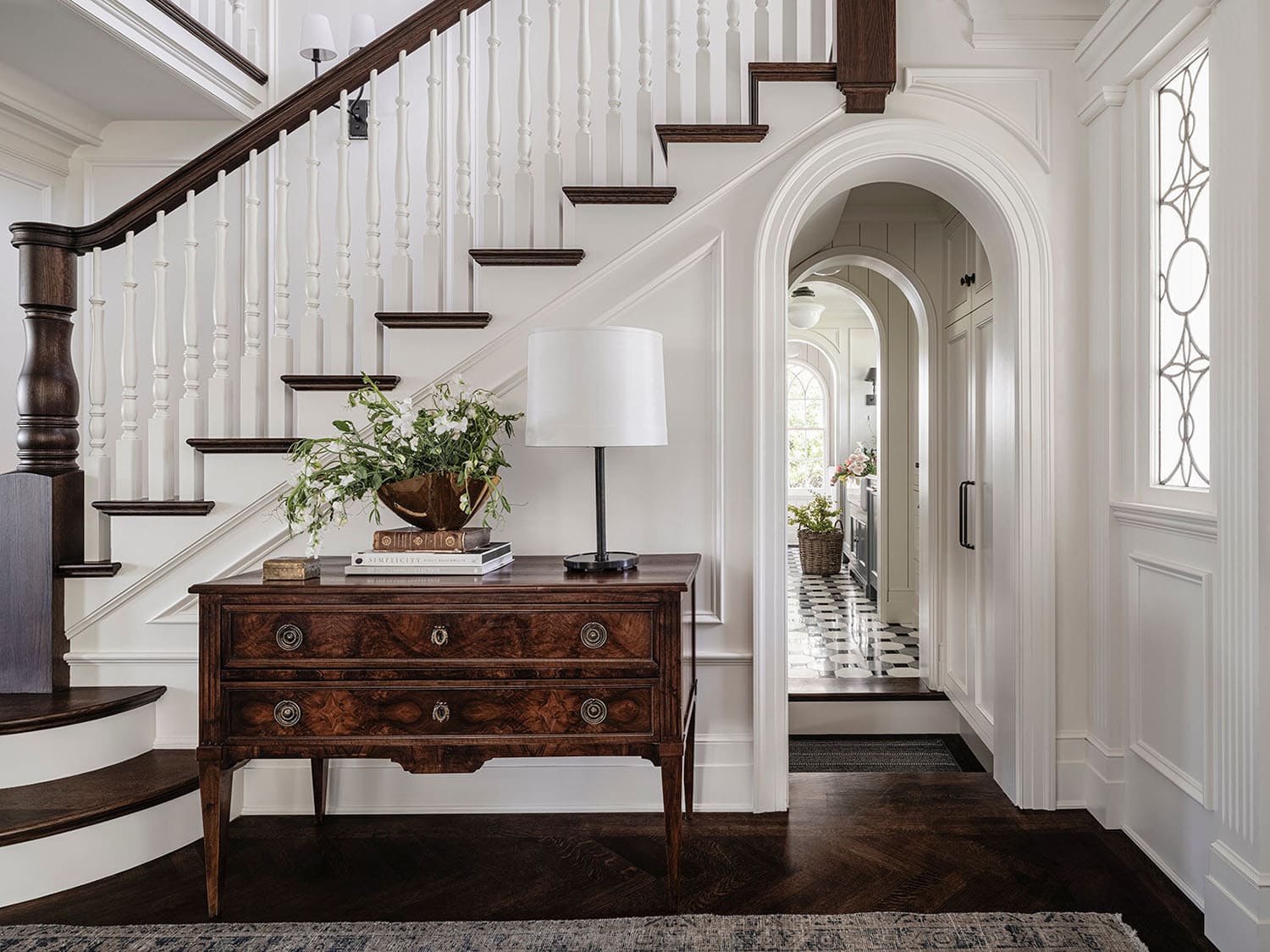 traditional style staircase with an arched hallway underneath