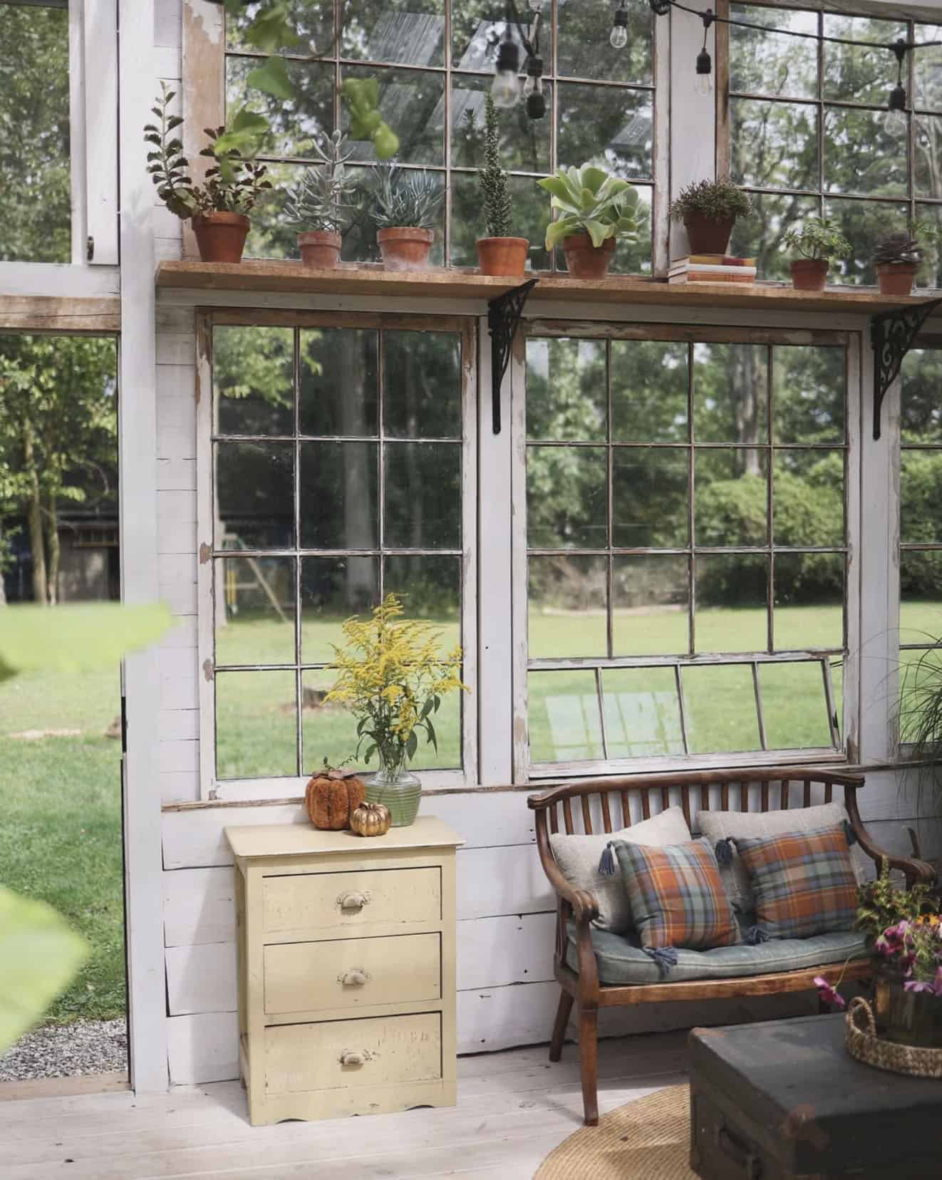 greenhouse interior with seating and planted pots on floating shelves in the window