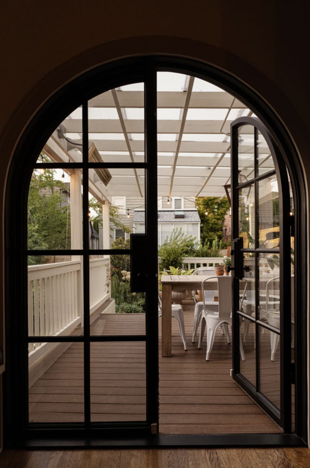 tudor home arched door leading to a pergola-covered patio