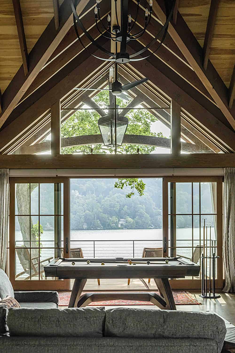 rustic family room with a billiard table and sliding glass doors overlooking the lake