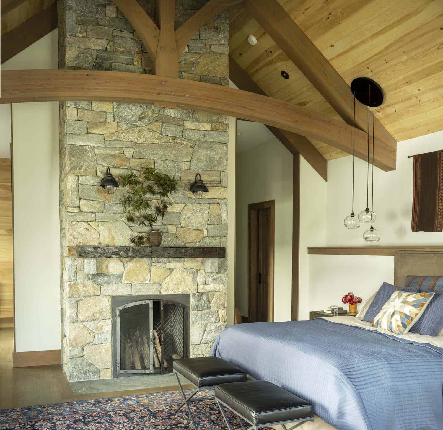 rustic bedroom with a fireplace and ceiling trusses