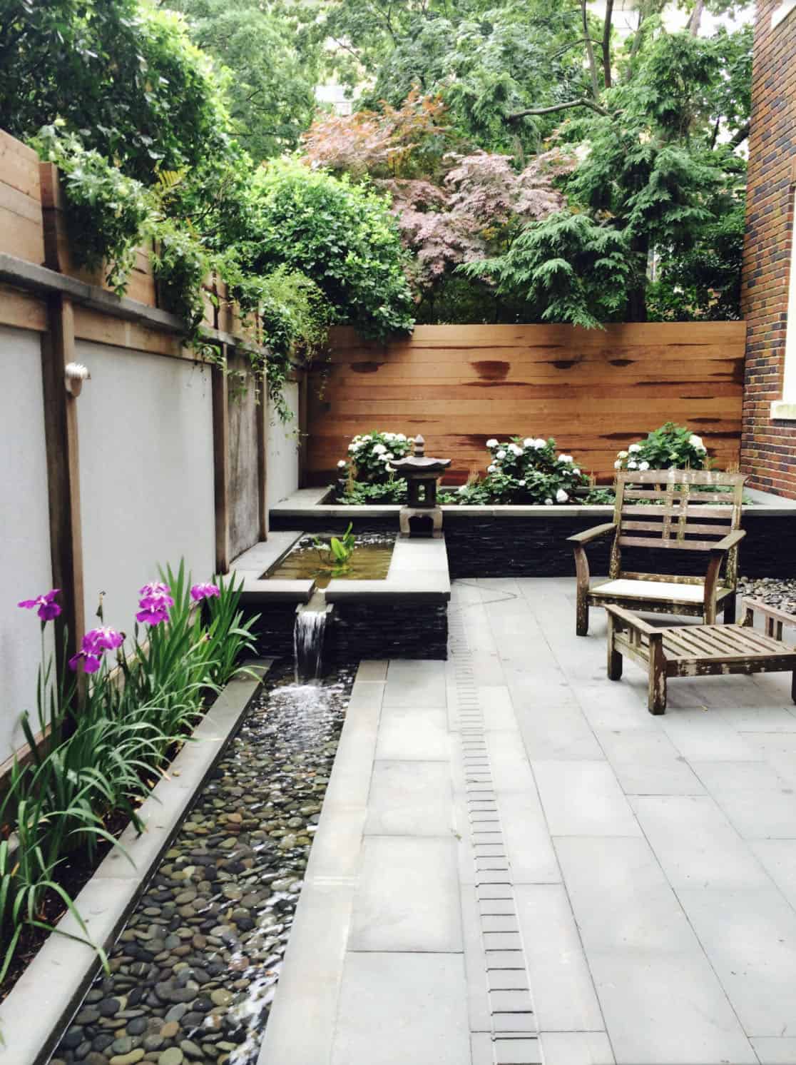 A small Asian-inspired backyard with a water feature and benches
