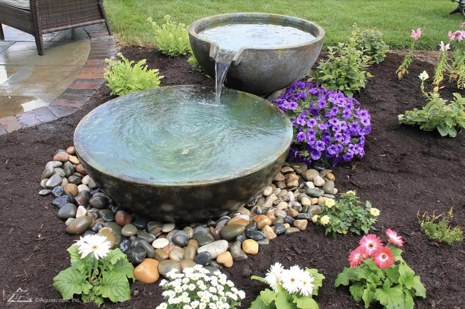 flower bed with a water fountain and river rocks