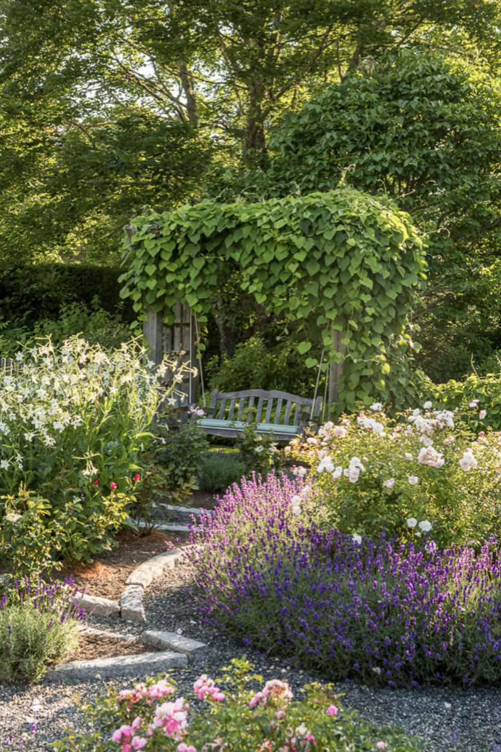 coastal garden with a stone and mulch path leading to a hanging swing and trellis