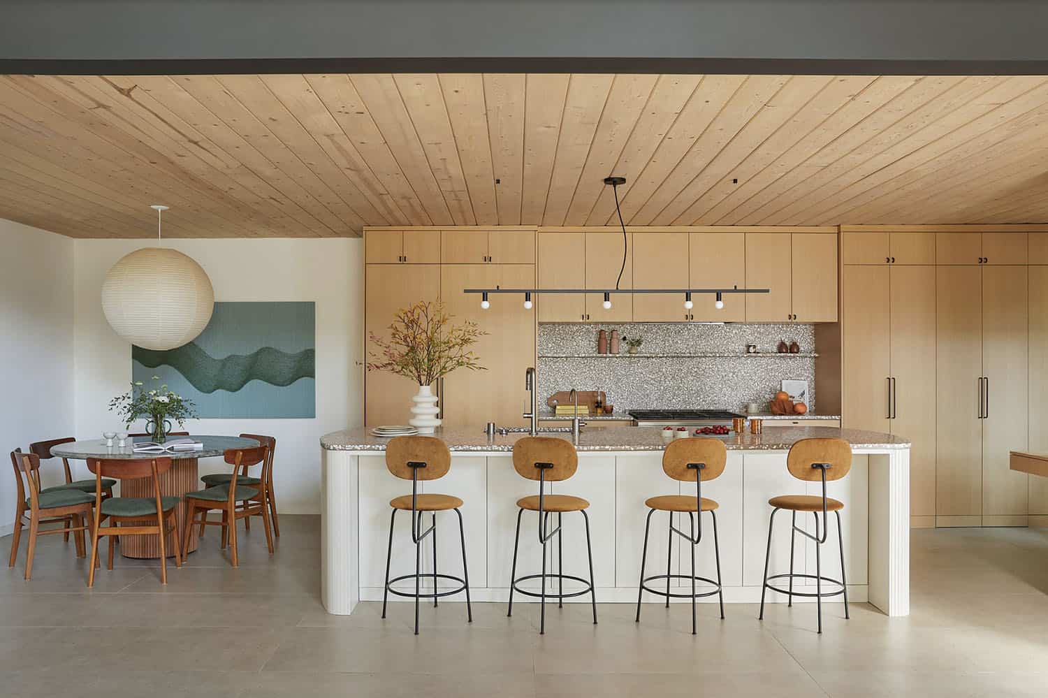 A kitchen with wooden ceiling and stools