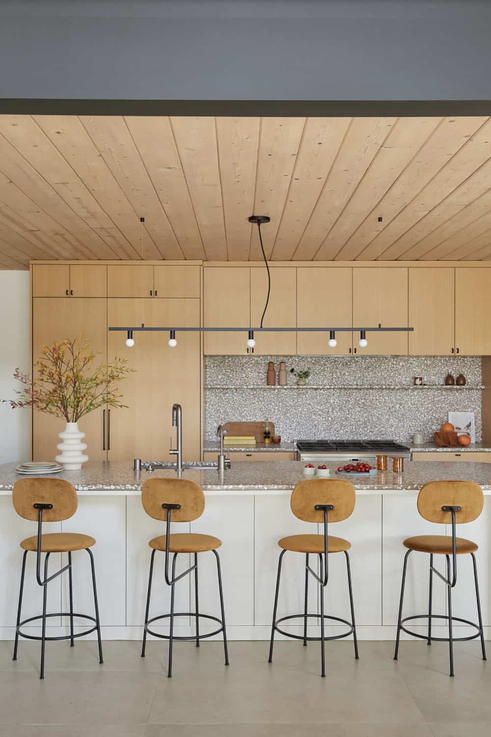 A kitchen with wooden ceiling and stools