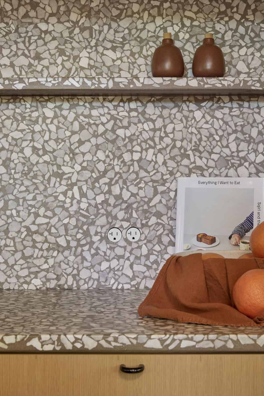 A kitchen with a shelf with oranges and a book