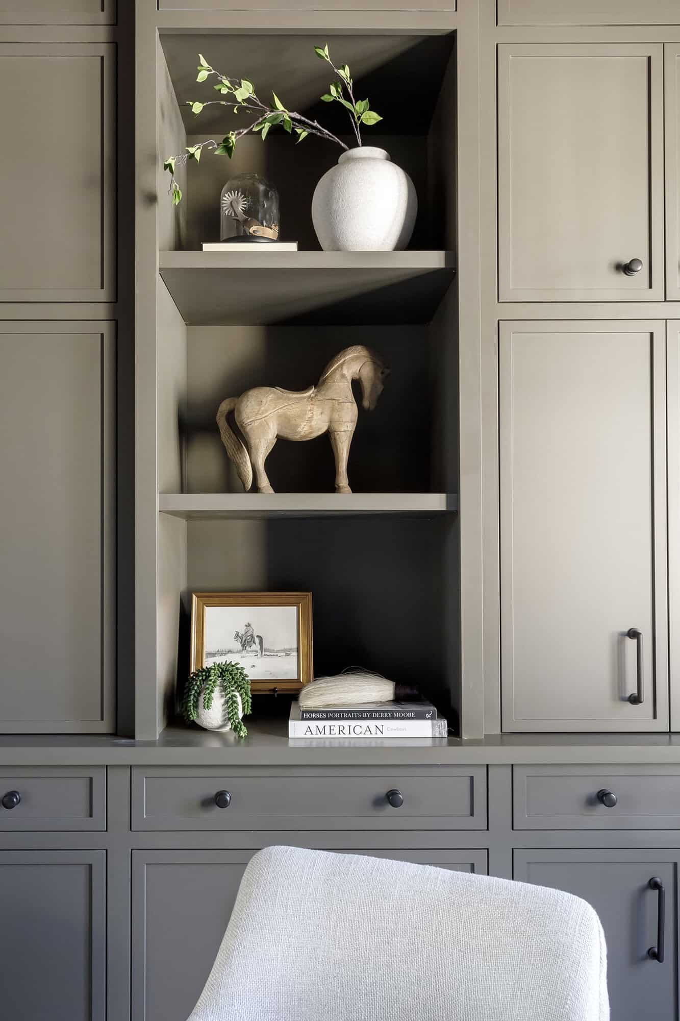 dark and moody office with built-in cabinets and display shelves