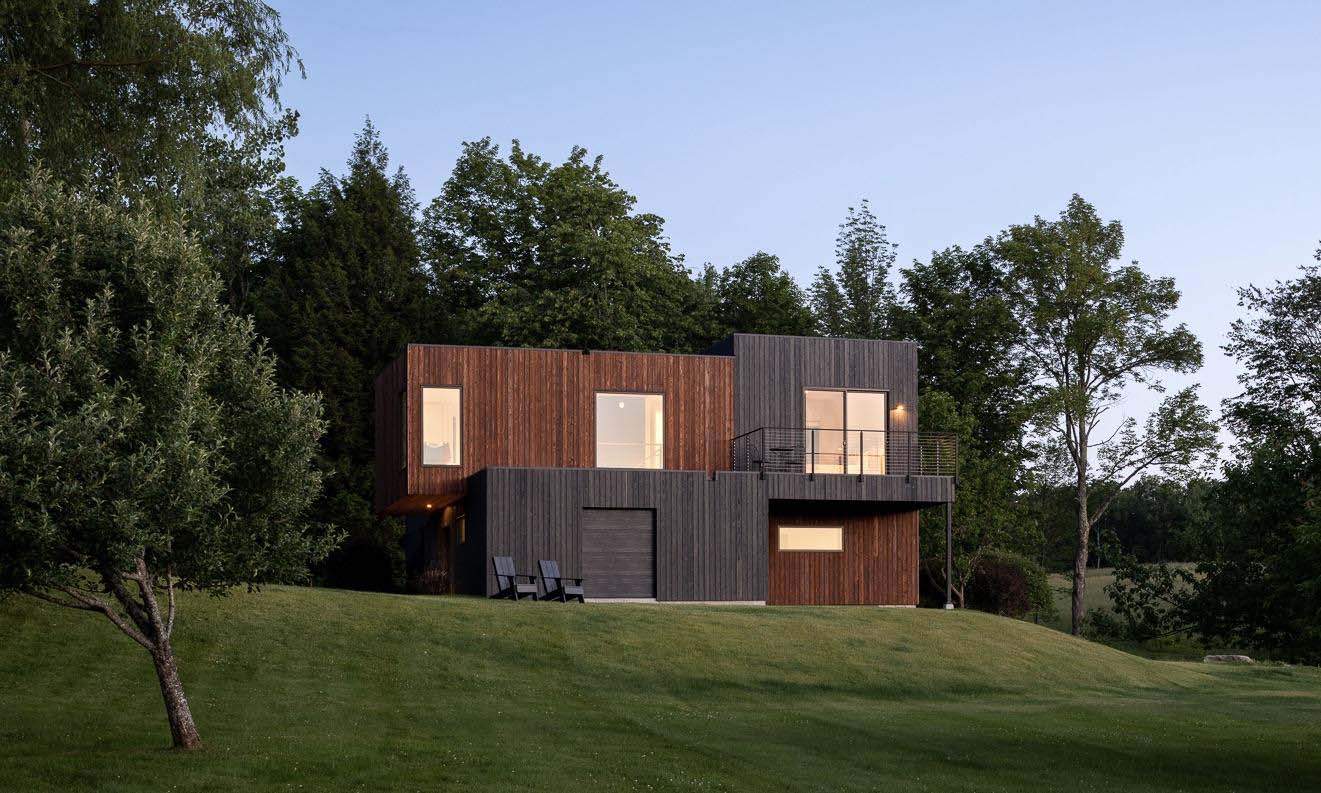 A modern house with a wooden exterior and a lawn