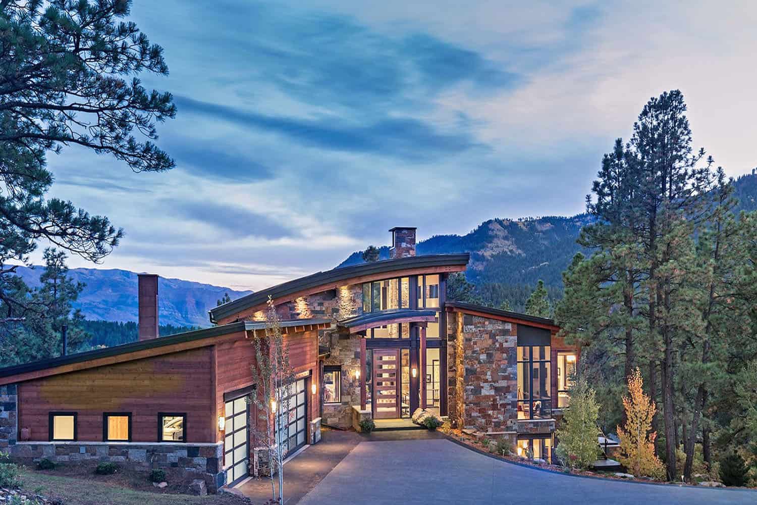 A modern mountain home with a driveway leading to it